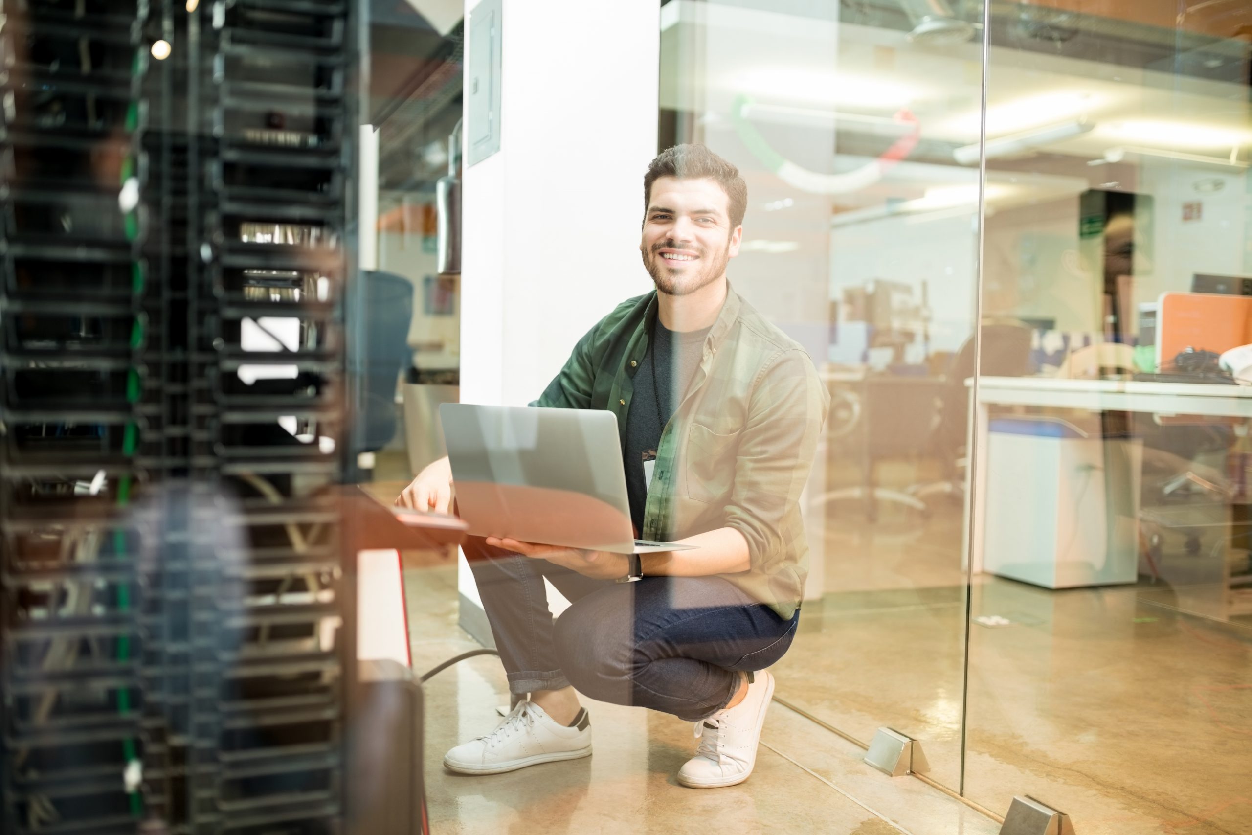 portrait happy young male network engineer with laptop hand working datacenter scaled